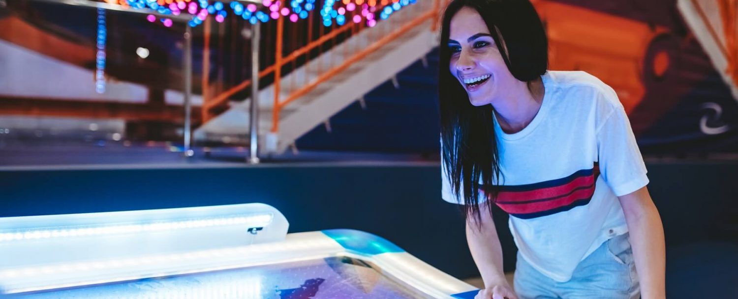 girl playing air hockey in arcade
